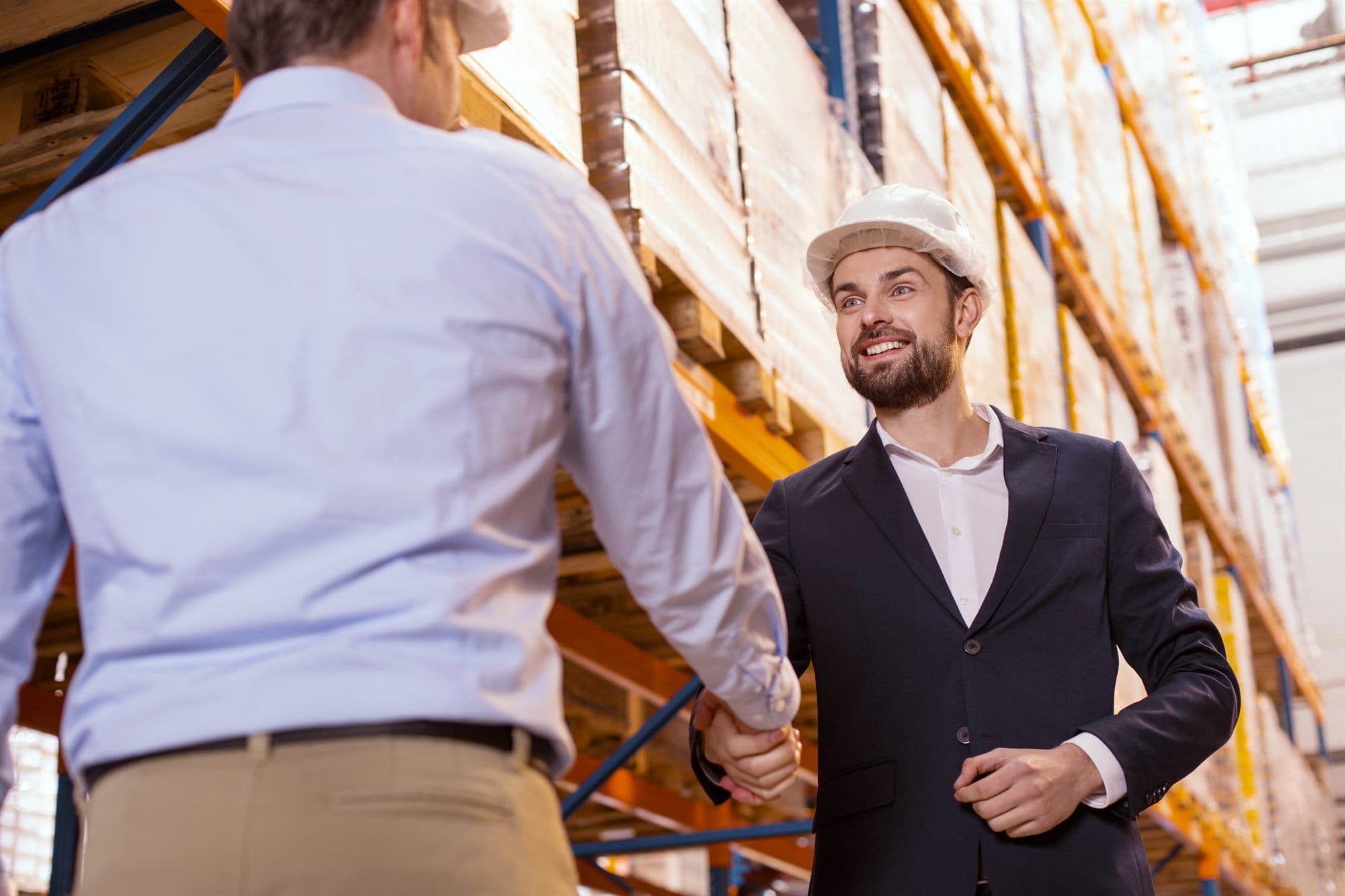 Manufacturer and distributor shaking hands on a warehouse floor